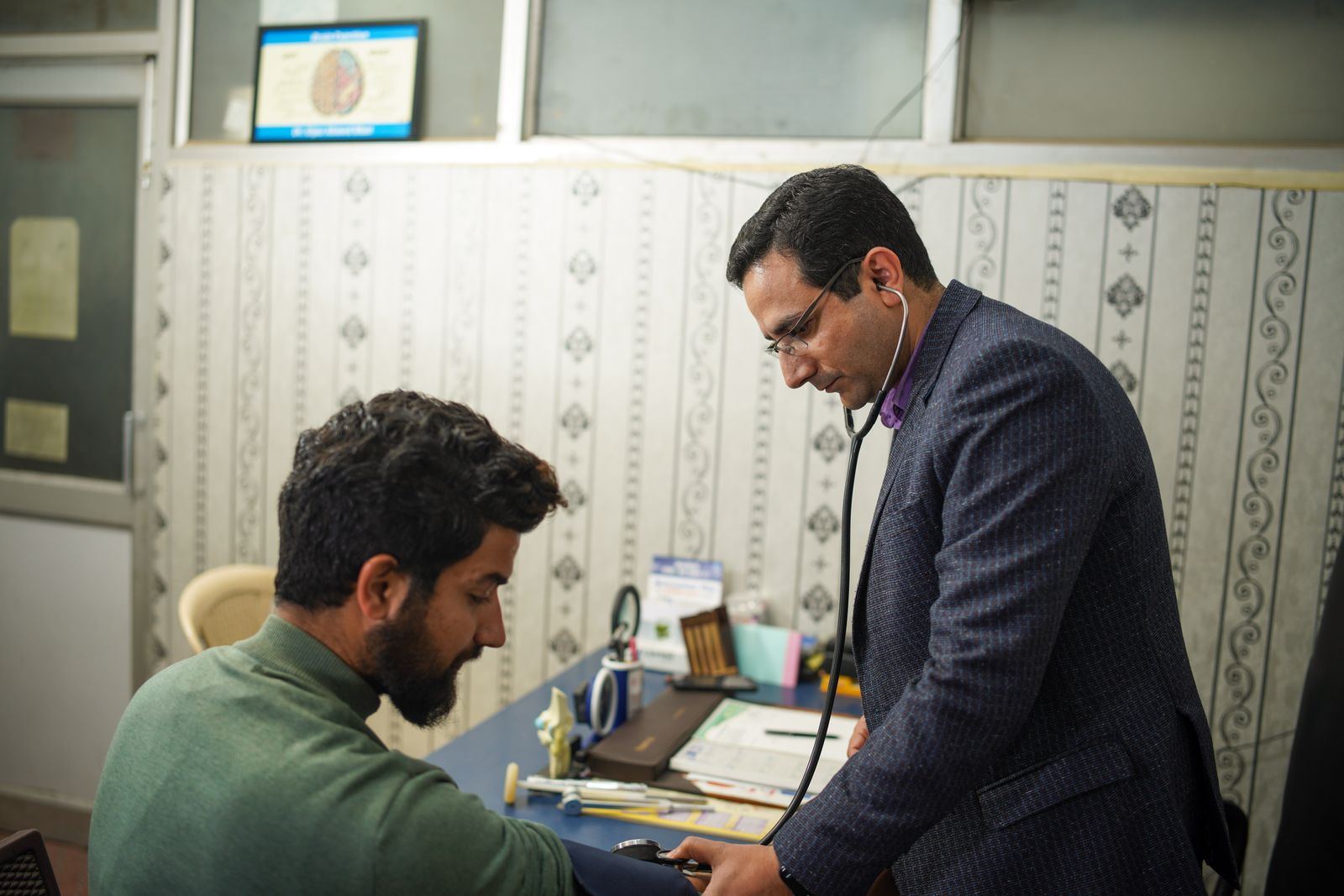 A doctor examining a patient with a stethoscope at a community health check-up